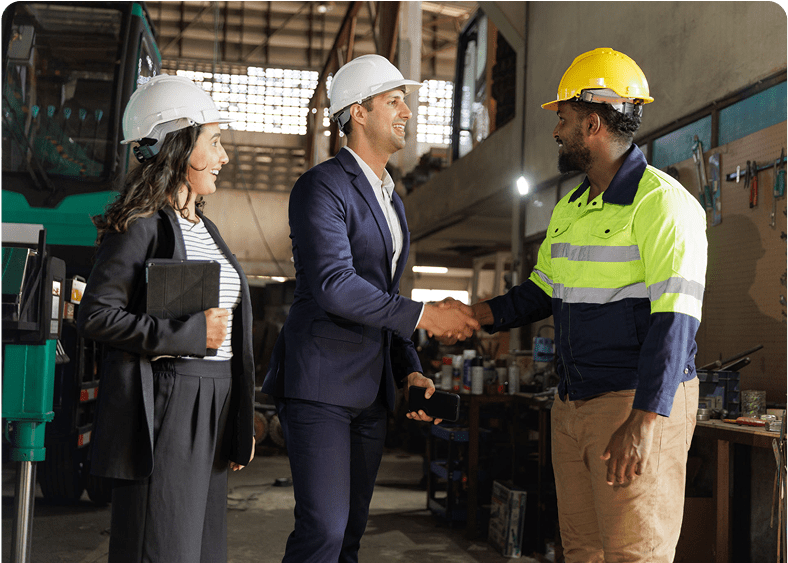 People in hard hats shaking hands indoors.