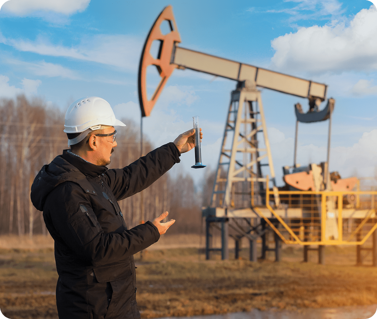 Man examining liquid near oil pumpjack.